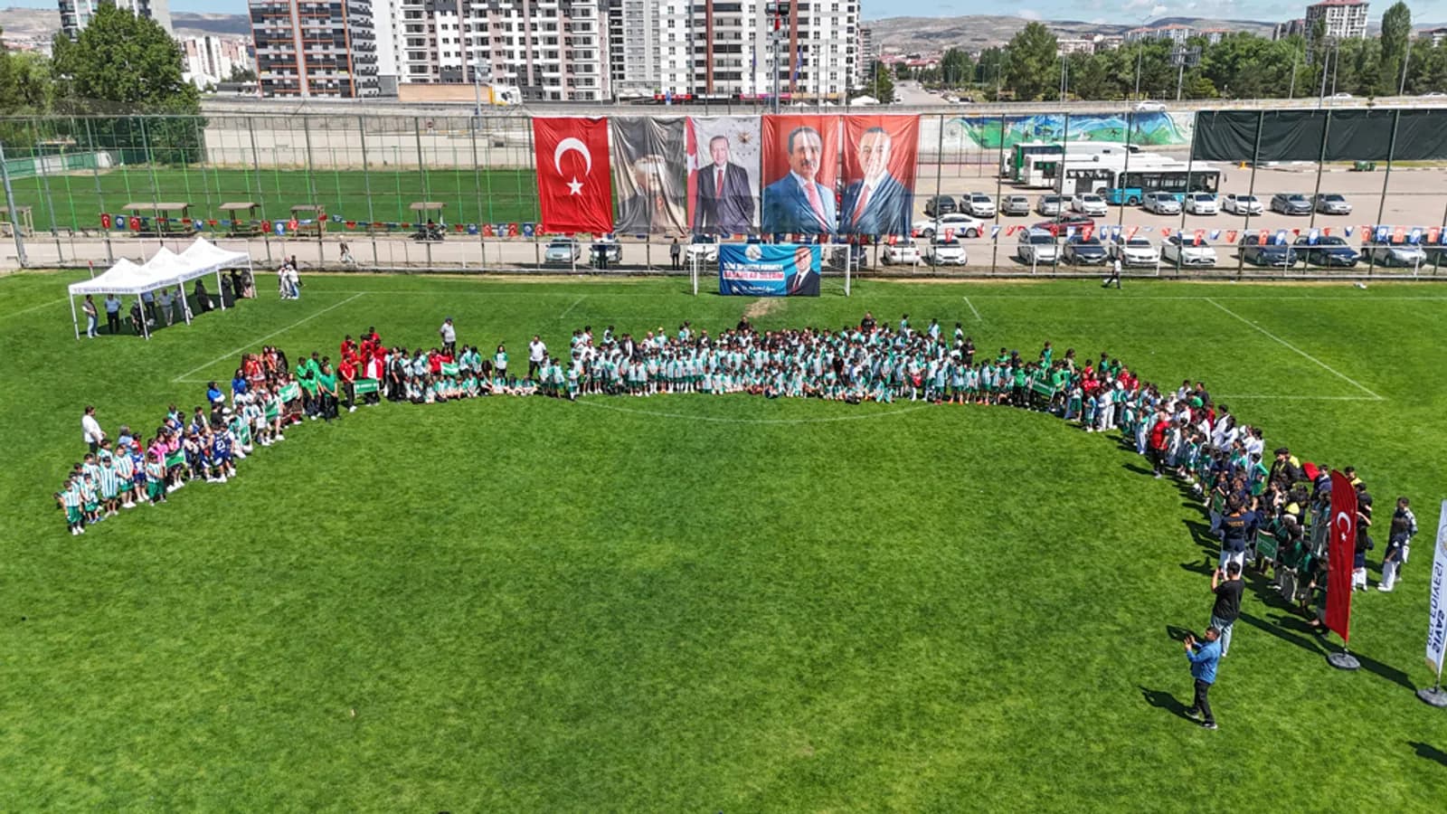Sivas Yaz Spor Okulları açılışında sahada büyük bir daire oluşturan öğrenciler ve antrenörler